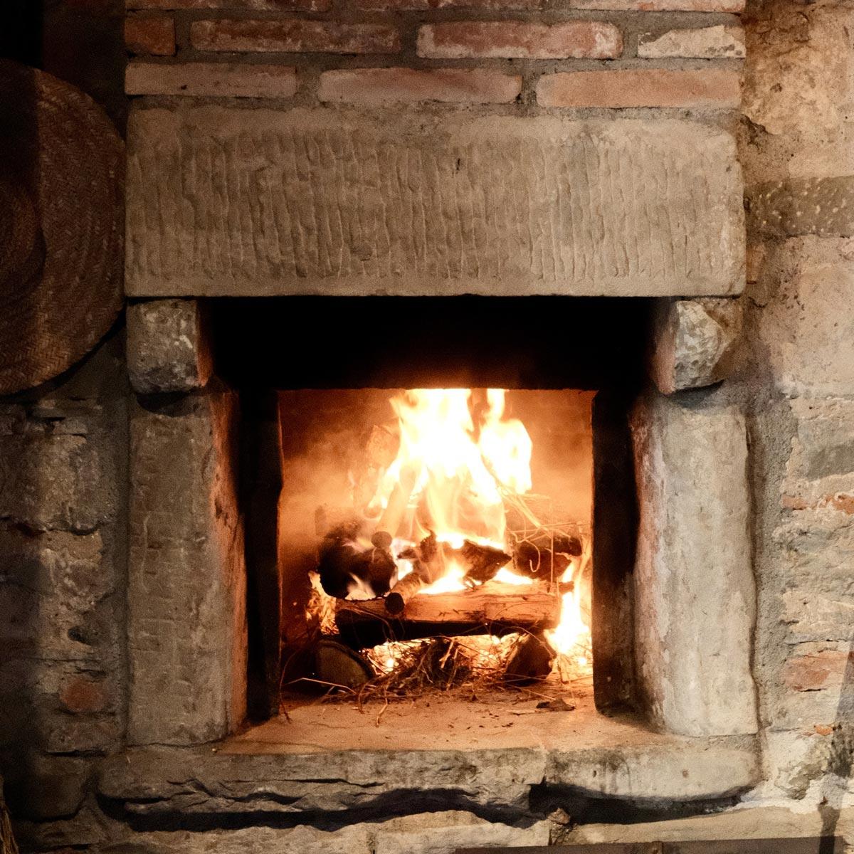 A wood-fired oven, fire blazing inside its stone surround