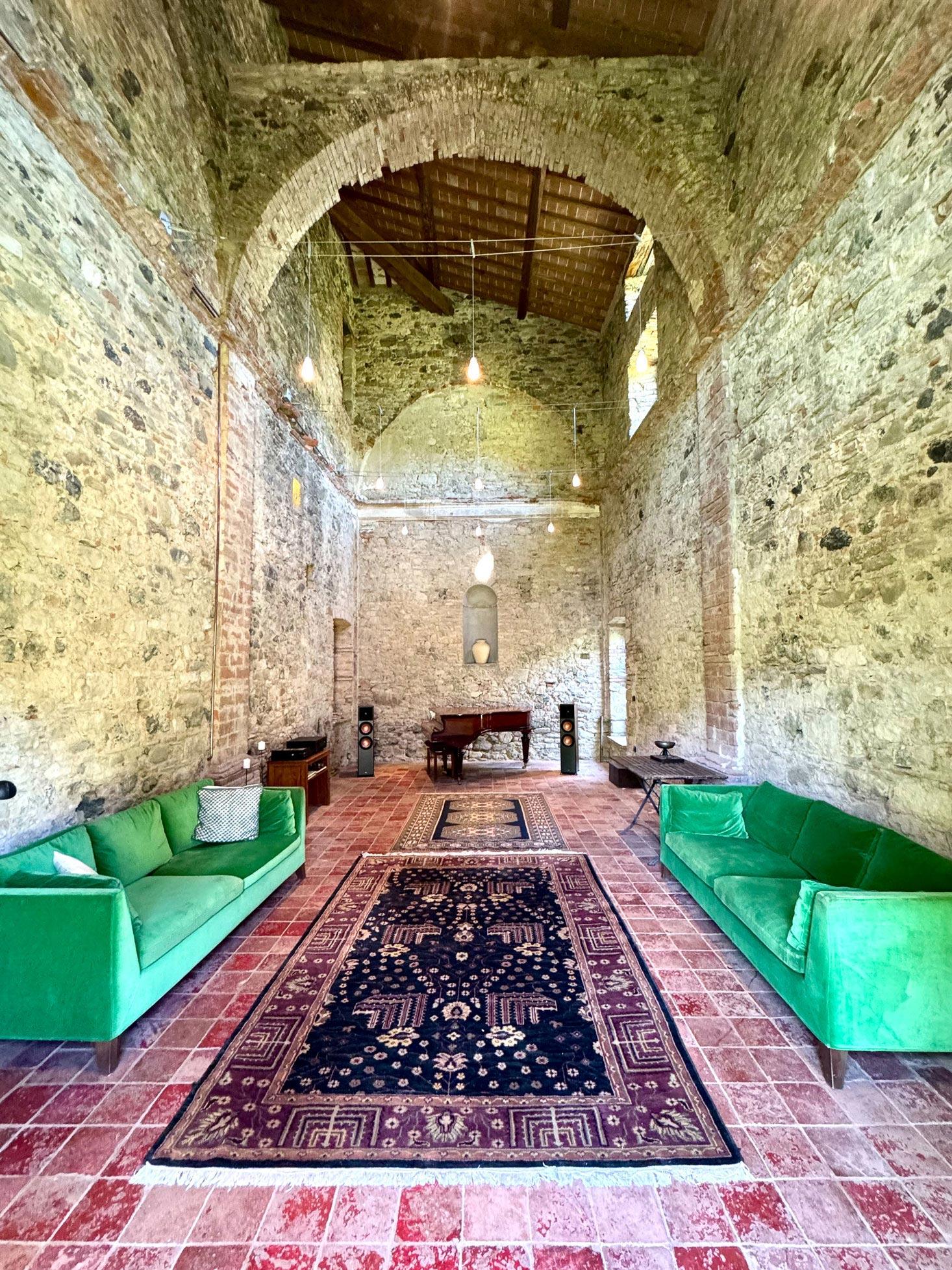 The vaulted chapel as a sitting room, two green velvet sofas facing each other across a Persian rug