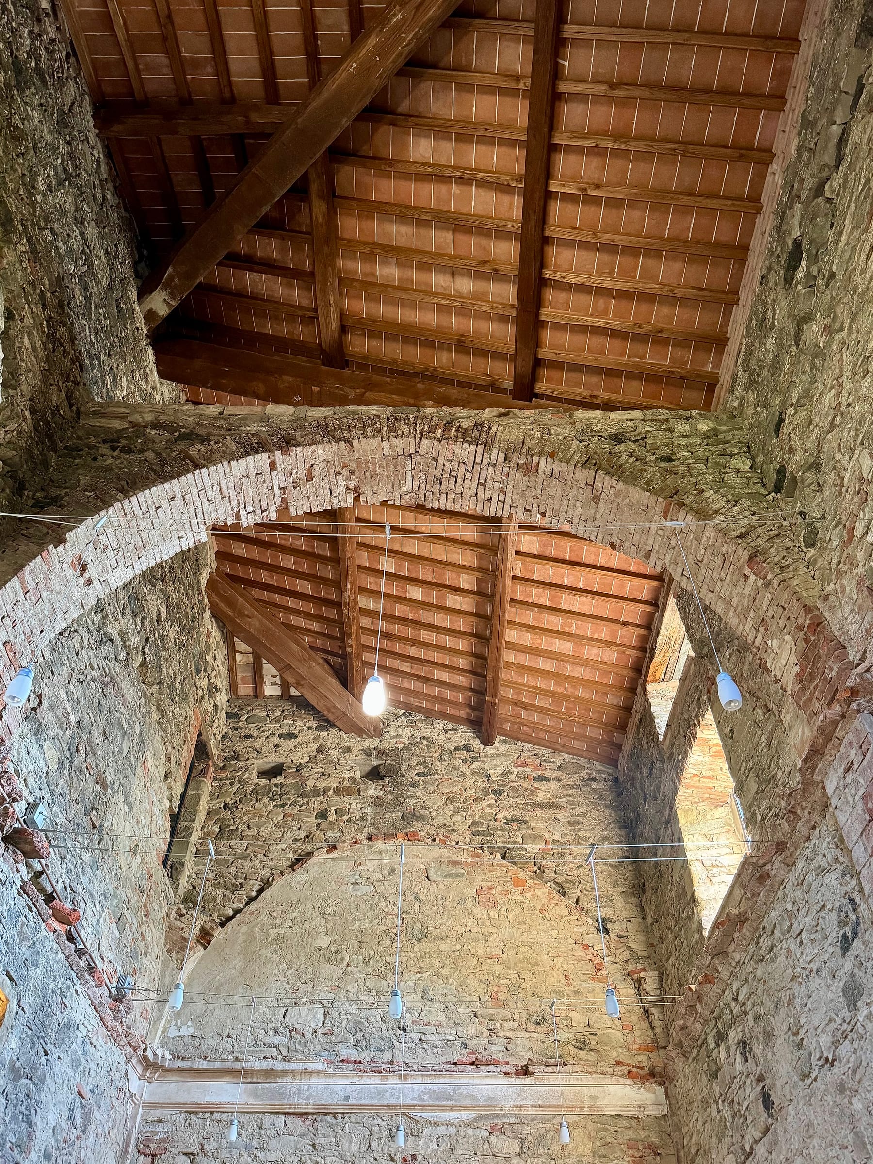 Looking up into the chapel roof, the remnant of the original brick vault meeting the timber and tile of the replacement